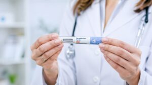 Close-up of a female doctor’s hands holding a semaglutide injection pen against a softly blurred clinical background
